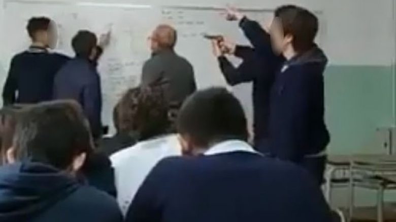 Filmohen nxënësit duke ia drejtuar revolen e plastikës në kokë profesorit